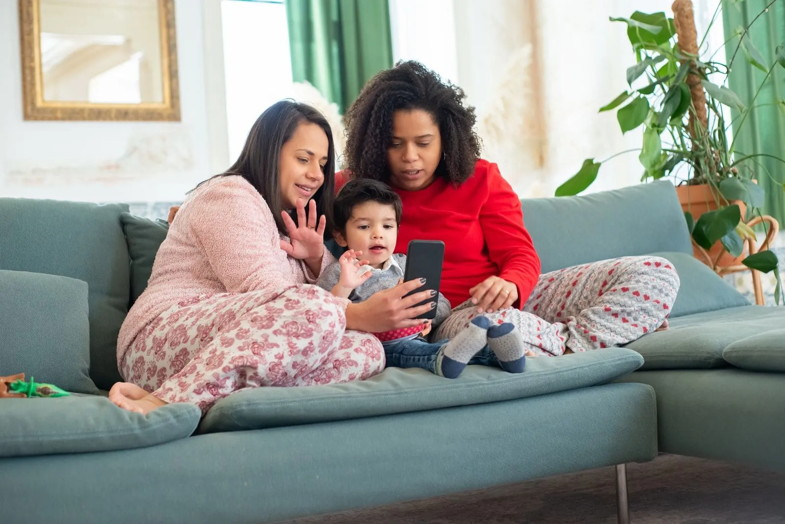 Two parents and a child on a sofa, reading a message together on a phone